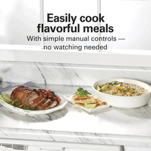 Black slow cooker with lid and two removable pots of food on the counter