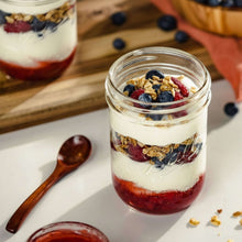 Ball wide-mouth mason jar filled with layered yogurt, granola, and berries