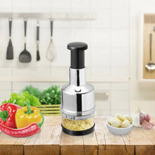 Stainless steel manual chopper with black top, on kitchen counter with vegetables