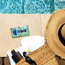 Orbit sweet mint sugar-free gum pack on patio tiles with straw hat nearby