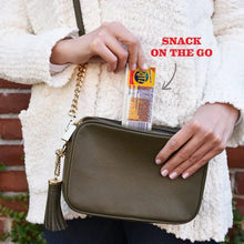 On-the-go crackers and cheese dip snack pack held near a crossbody bag