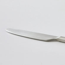 Satin stainless steel dinner knife with smooth blade and ribbed handle close-up