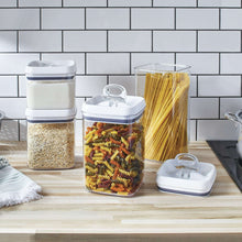 Food storage containers with clear bodies and white lids, filled with dry goods