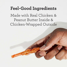 Hand holding an orange chicken-wrapped dog chew stick