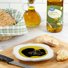 Extra virgin olive oil bottle beside plate of oil and bread