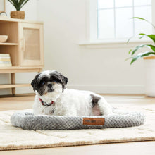 Gray crate mat pet bed with a dog resting on it, plush padded edges.
