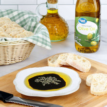 Extra virgin olive oil bottle with green label, shown with bread and dipping plate.