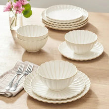 Cream scalloped stoneware bowls and plates, dinnerware set on tabletop