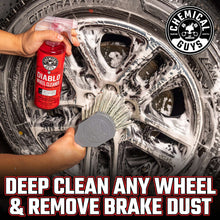Wheel cleaner bottle and gray cleaning pad scrubbing a wheel