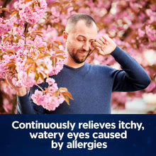 Man holding his nose near pink blossoms