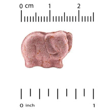 Purple-pink chewable vitamin tablet with size marks on a ruler