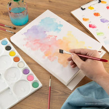 Watercolor paper pad sheet with pastel watercolor wash and paintbrush