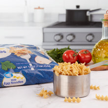 Wide egg noodles in metal cup with Great Value noodle bag on counter