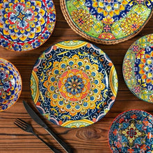 Decorative ceramic plates and bowls set with mandala patterns on dark blue