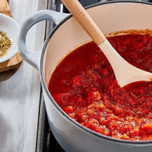 Pot of red tomato sauce with wooden spoon.