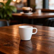 White coffee mug with curved handle on a wooden table.