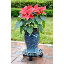 Black round plant caddy with lattice top under a glazed planter with flowers