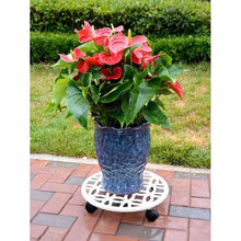 Off-white circular plant caddy with cutout pattern and four black support feet