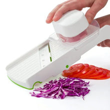 White multi slicer with clear food guard and green base, slicing tomato