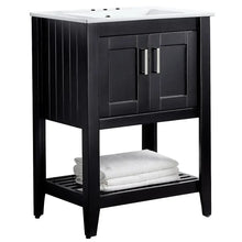 Black bathroom vanity with white countertop and lower shelf with towel.