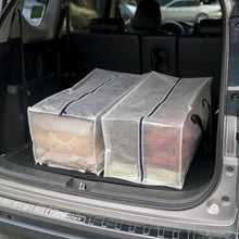 Clear moving storage bag pair with black trim in a car trunk