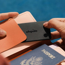 Black Chipolo LOOP card tracker with chipolo logo, held between leather cards