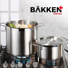 Stainless steel stockpot with lid on stovetop, beside another lidded pot