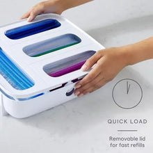 White bag dispenser with colored rolls; hand lifts removable lid for refills