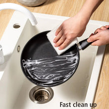 Black non-stick skillet being wiped clean with a cloth