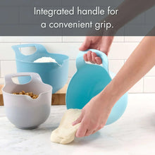 Blue plastic mixing bowl with integrated handle, used for preparing dough on counter