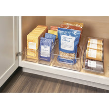 Clear kitchen bin set in an open cabinet, holding assorted pantry packages