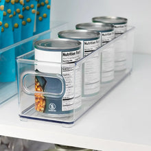 Clear kitchen bin with stacks of canned foods, showing nutrition label side