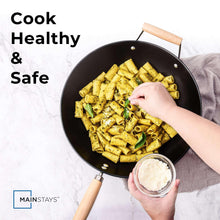 Black wok with wooden handle holding diced vegetables and seasoning