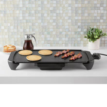 Electric griddle with cooking plate holding pancakes, bacon, and eggs