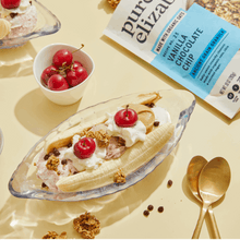 Banana split dessert with granola topping and small bowls, plus granola pouch in view