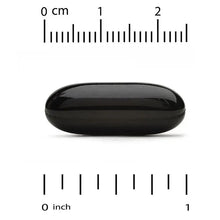 Black softgel capsule next to cm and inch measurement rulers