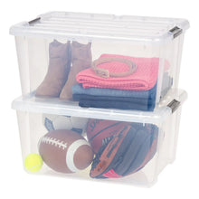 Clear plastic storage bin set, open top with black buckles holding folded clothes and balls