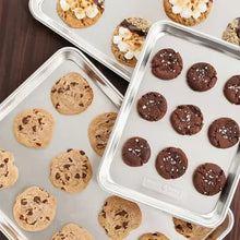 Natural aluminum cookie sheet with assorted baked cookies on a tray surface