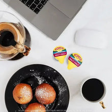 Half-and-half creamer sachets and coffee on kitchen counter with skillet