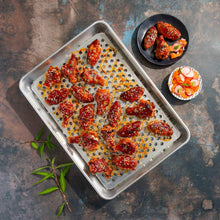 Oven crisping rack tray with roasted wings on a perforated insert