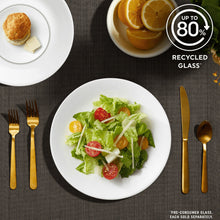 White glass salad plate with mixed greens, cherry tomatoes, and gold cutlery