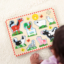 Farm animal sound puzzle board with loose wooden peg pieces on a rug