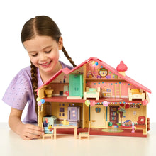 Toy playset house with colorful rooms and figures, held by a child
