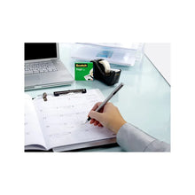 Scotch Magic Tape in use on documents on a desk, hand applying tape