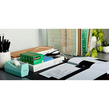 Scotch Magic Tape rolls in teal dispenser on desk with papers and tools