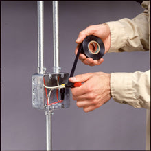Hands applying black electrical tape to wiring at a metal electrical box