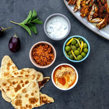 Serving tray with flatbread and small bowls of dips for picnic-style portions