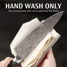 Chef knife blade with gray Damascus pattern, water droplets, and dark wood handle