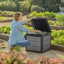 Grey resin deck box with hinged lid open, showing storage compartment for outdoor items