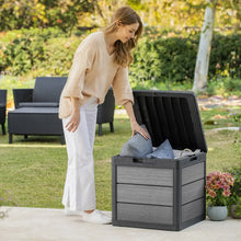 Grey resin deck storage box with lid open, displaying folded fabric inside